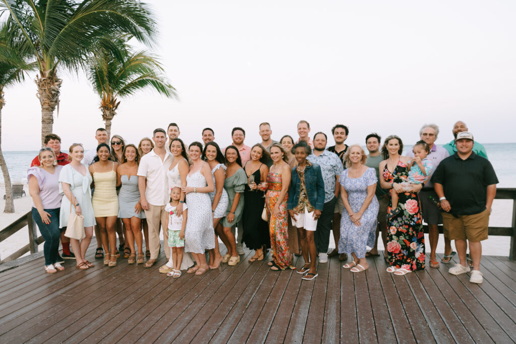 Group photograph of family and friends on a wooden patio on the beach with palm trees