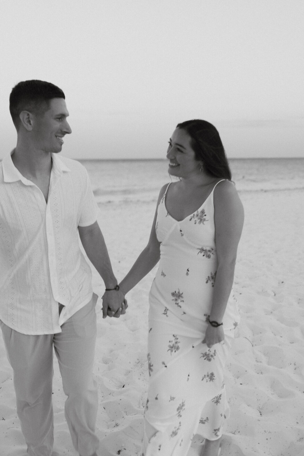 Groom and Bride holding hands and gazing at one another on a beach