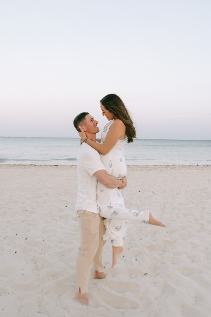 Groom lifting and embracing Bride on white sand beach