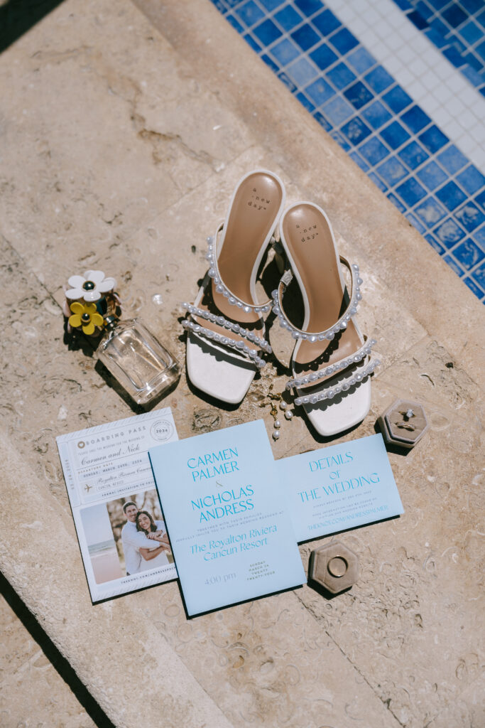 Wedding shoes, wedding rings, perfume, and stationary  on marbled concrete with blue mosaic tiles