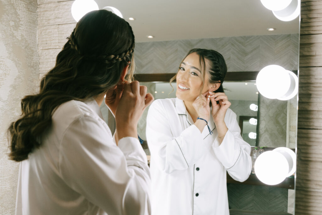 Bride in a white pajama set putting in earrings