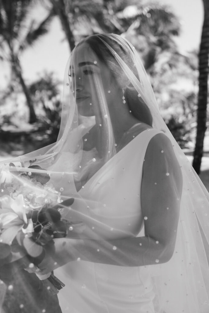 Close up of Bride gazing in the distance with flowers underneath a pearl netted cathedral length veil 