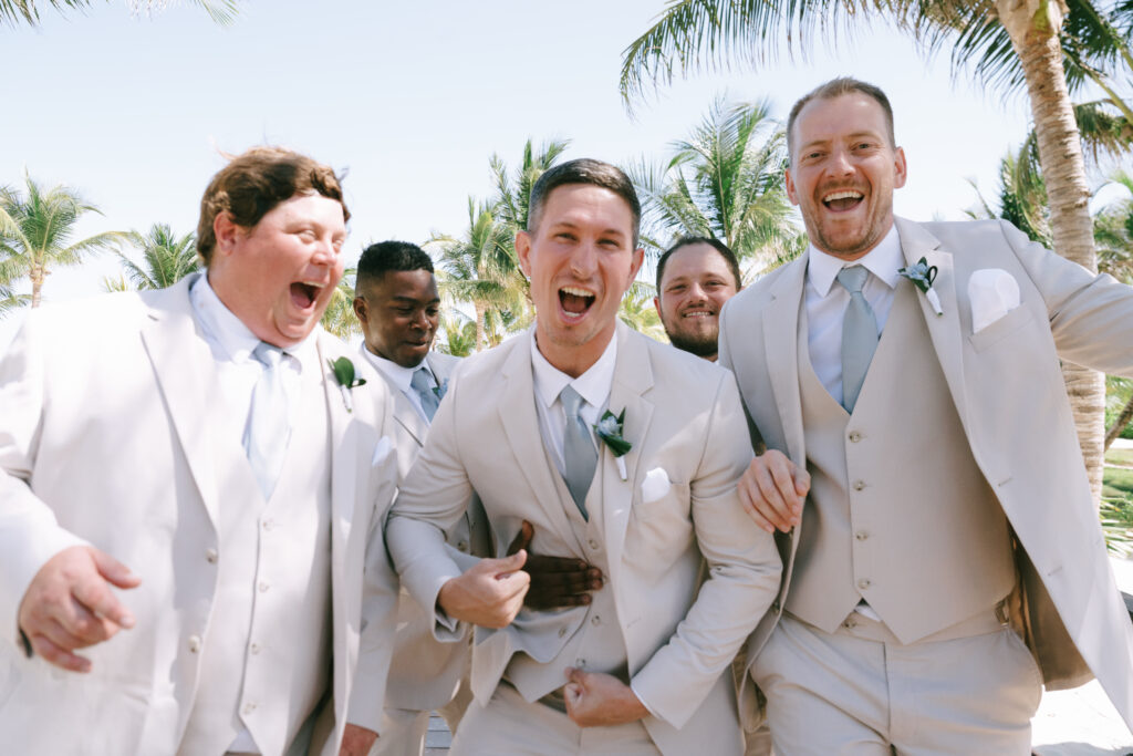 Close up of Groom and Groomsmen in beige tuxedos with blue ties smiling