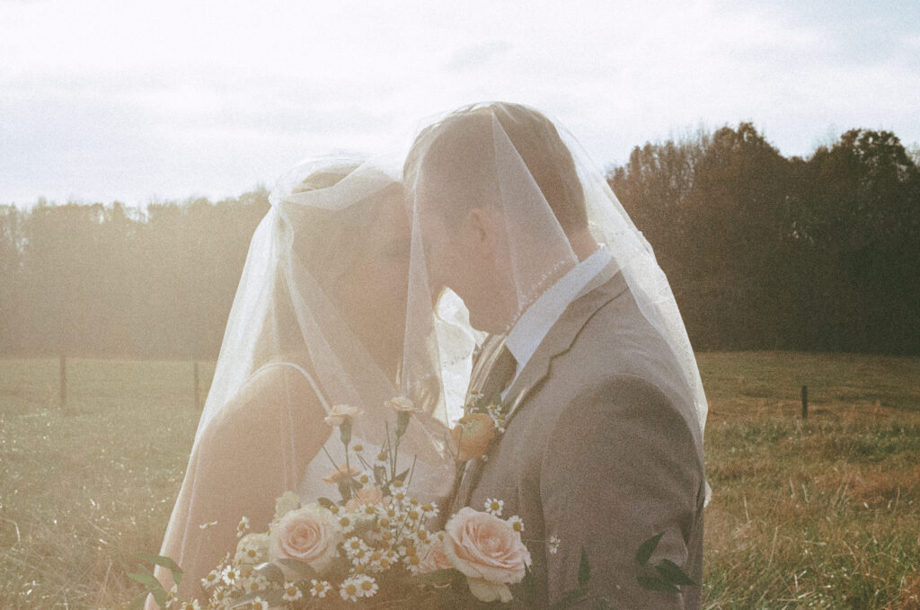 Bride and Groom touch noses and smile under the bride's veil.