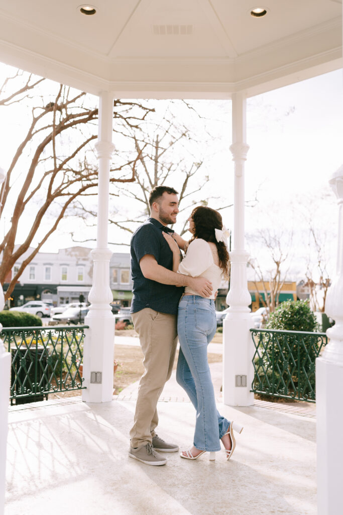 Couple embracing and gazing at each other under a white gazebo in The Marietta Square