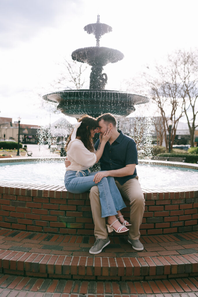 Couple cuddling on a brick fountain in The Marietta Square