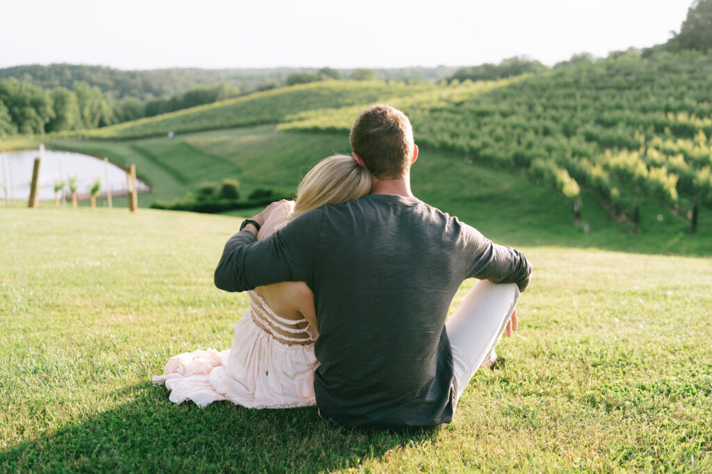 Couple sitting and embracing in front of a large vineyard at Montaluce Vineyard and Winery