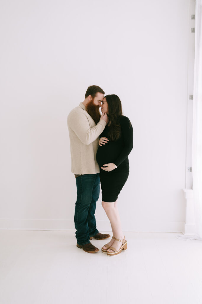 Couple standing and embracing in a white washed studio