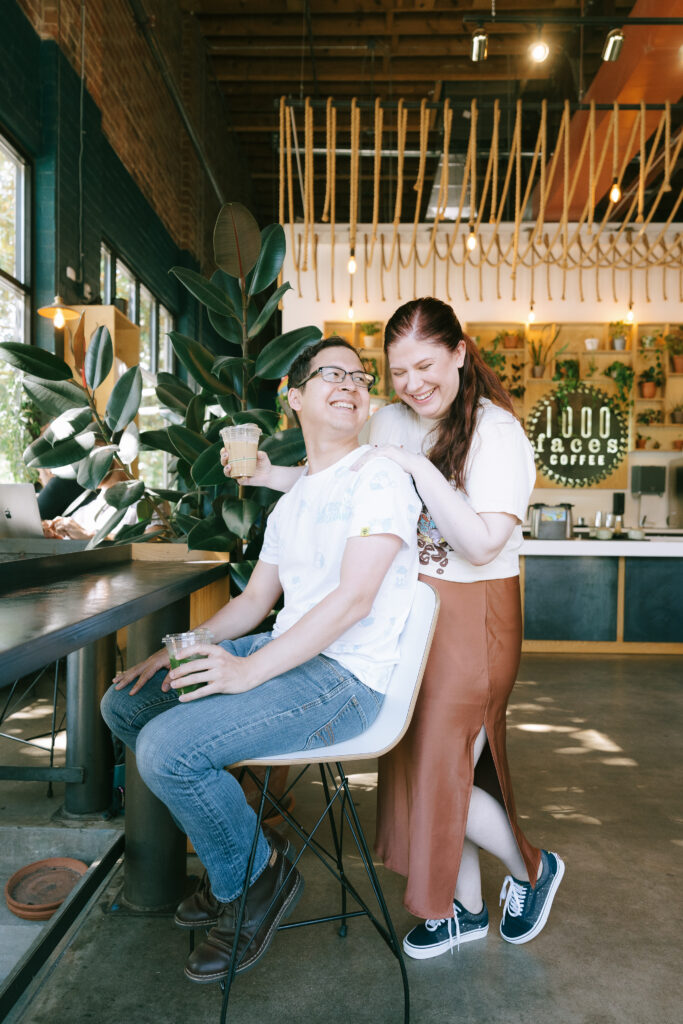 Couple sitting and laughing together with coffee cups in hand at a coffee shop