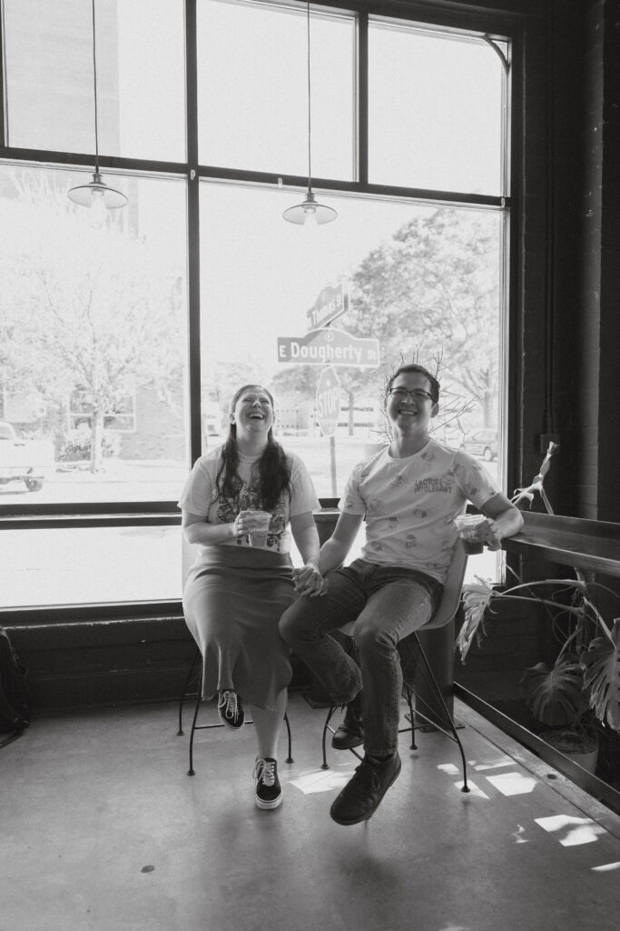 In black and white of a couple sitting and laughing at a high-top counter