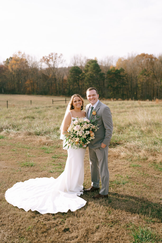 Bride and Groom stand side by side facing forward in a field of golden grass.