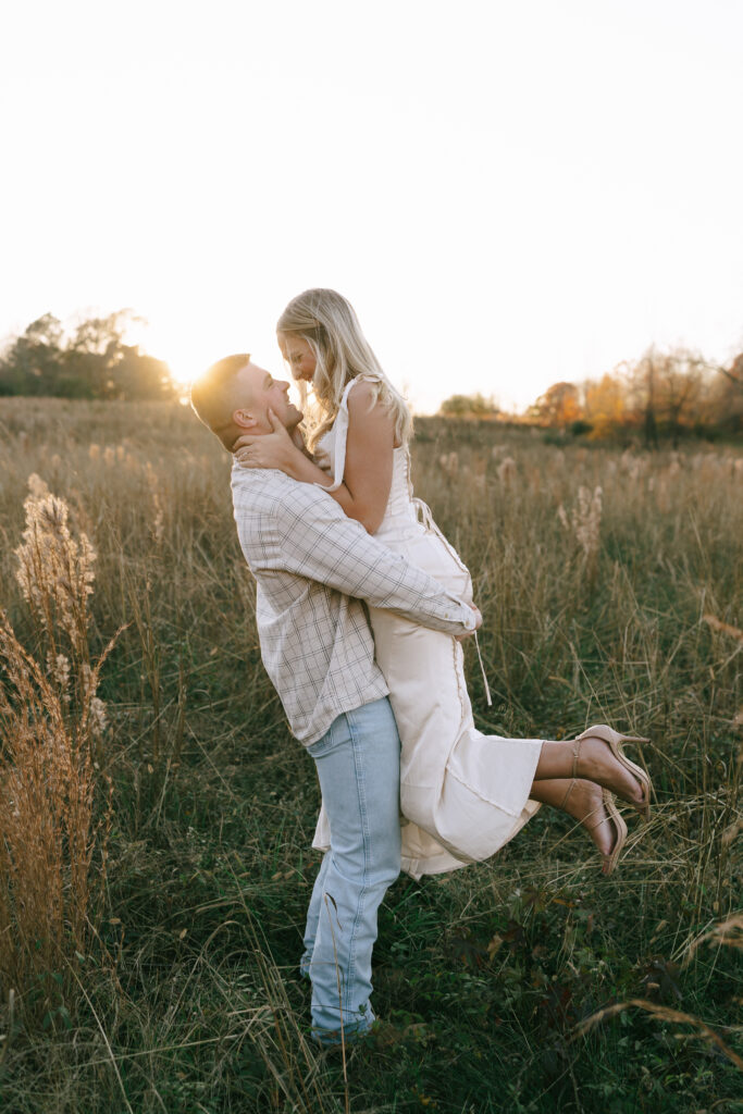 Man lifting woman in a field of golden grasses at Vaughters Farm