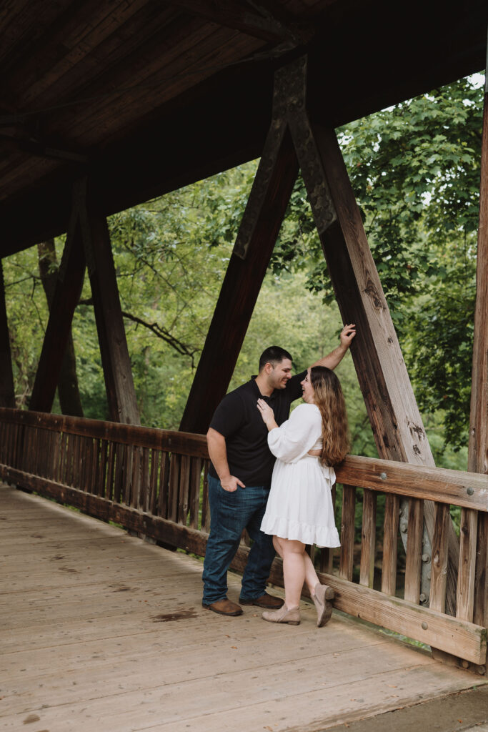 Couple standing together laughing on a wooden bridge at The Roswell Mill