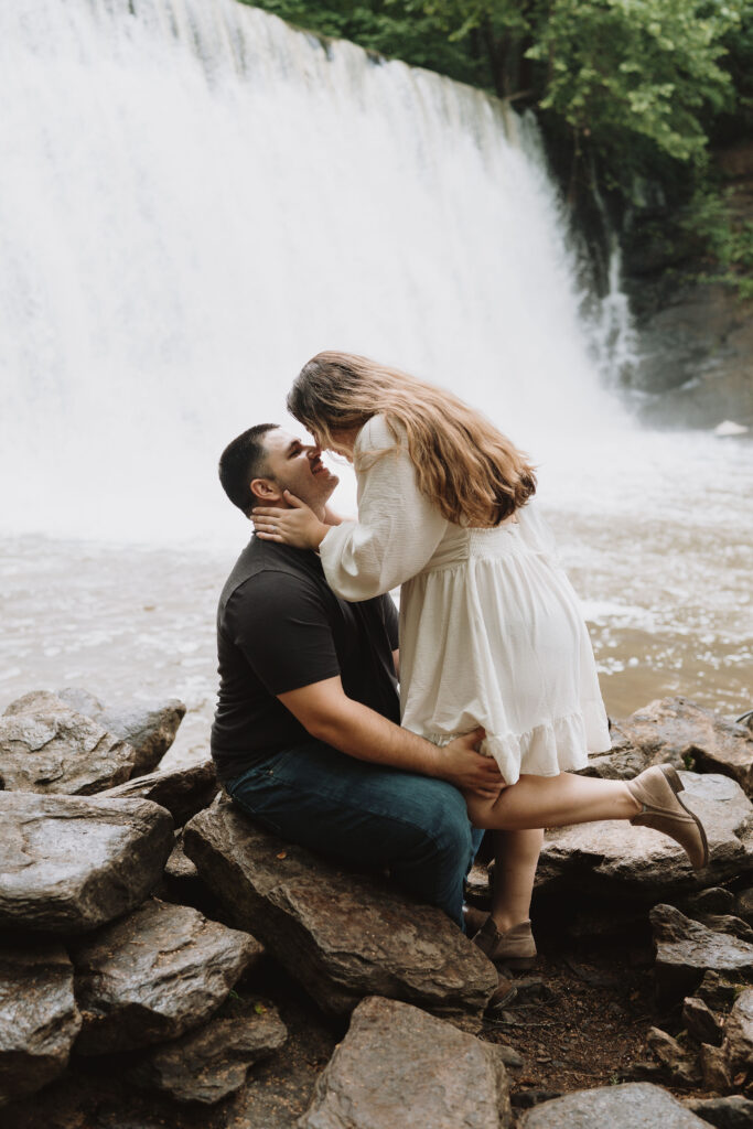 Couple embracing in front of a waterfall at The Roswell Mill