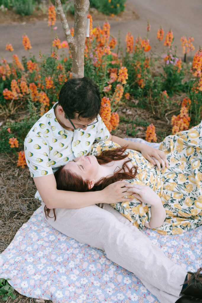 Woman laying in man's lap surrounded by orange flowers in the State Botanical Gardens of Georgia