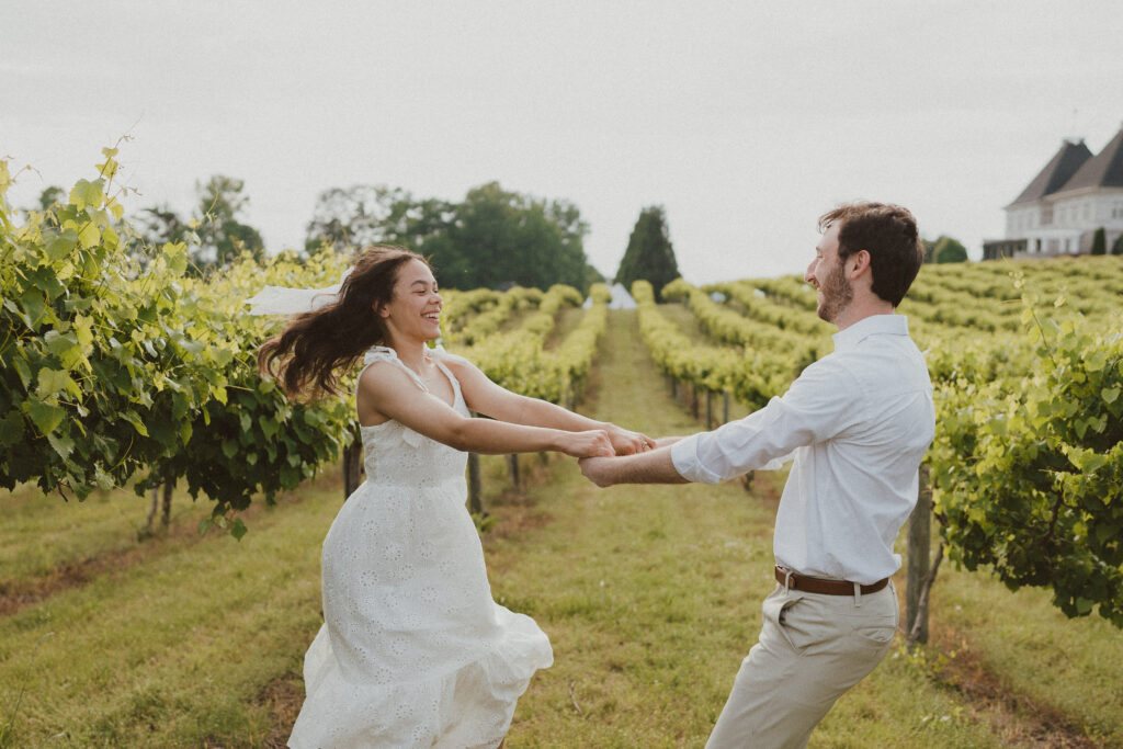 Couple dancing and laughing between rows of grape vines at Chateau Elan