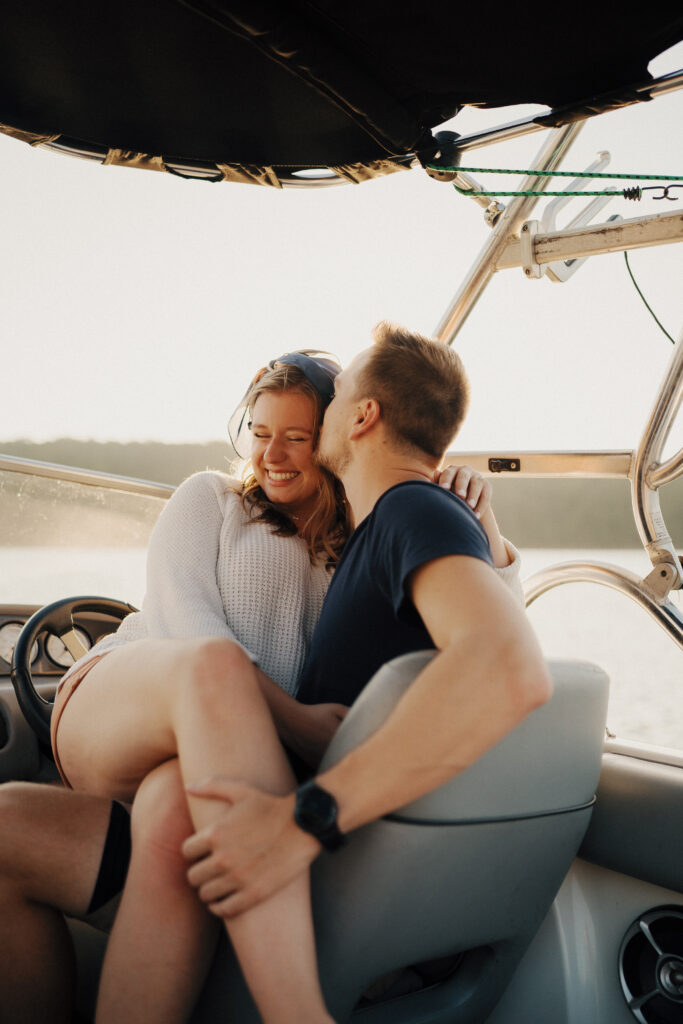 Couple embracing and kissing in the captain's seat of a small boat