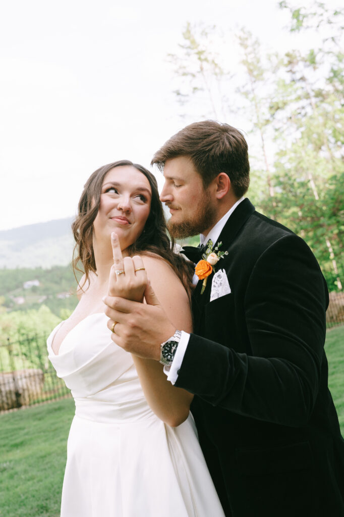 Bride and groom gazing at each other with bride holding up her ring finger.