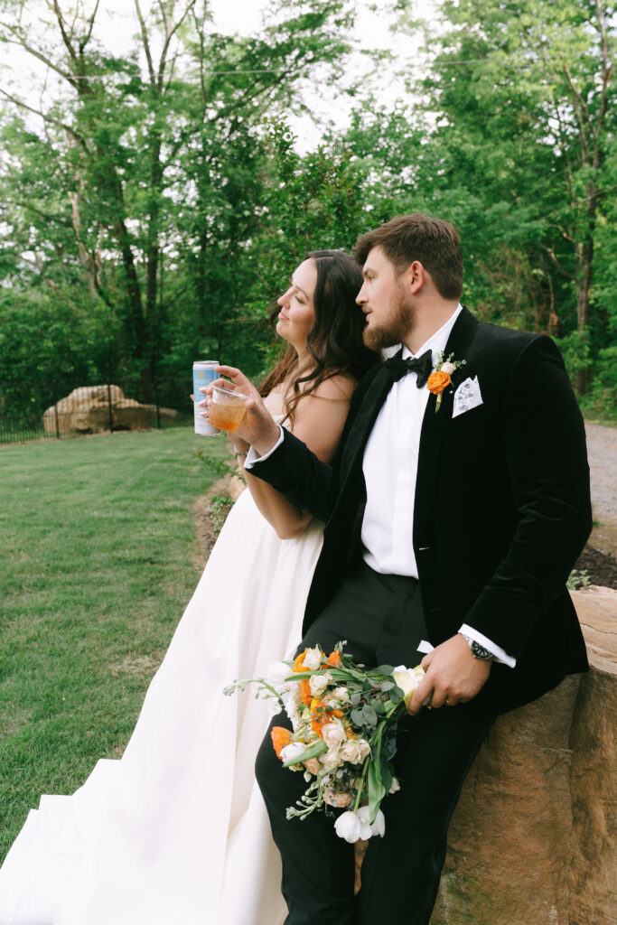 Bride and groom looking into the distance and doing "cheers" with drinks.