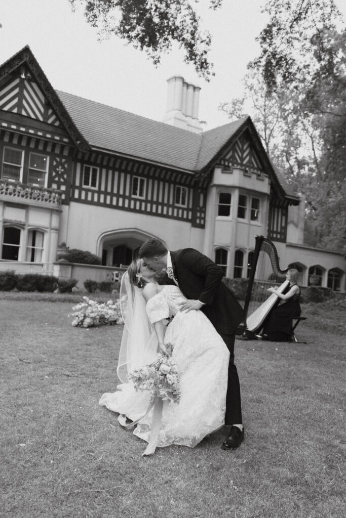 Groom dipping bride for a kiss while harpist plays in the background at Callanwolde Fine Arts Center