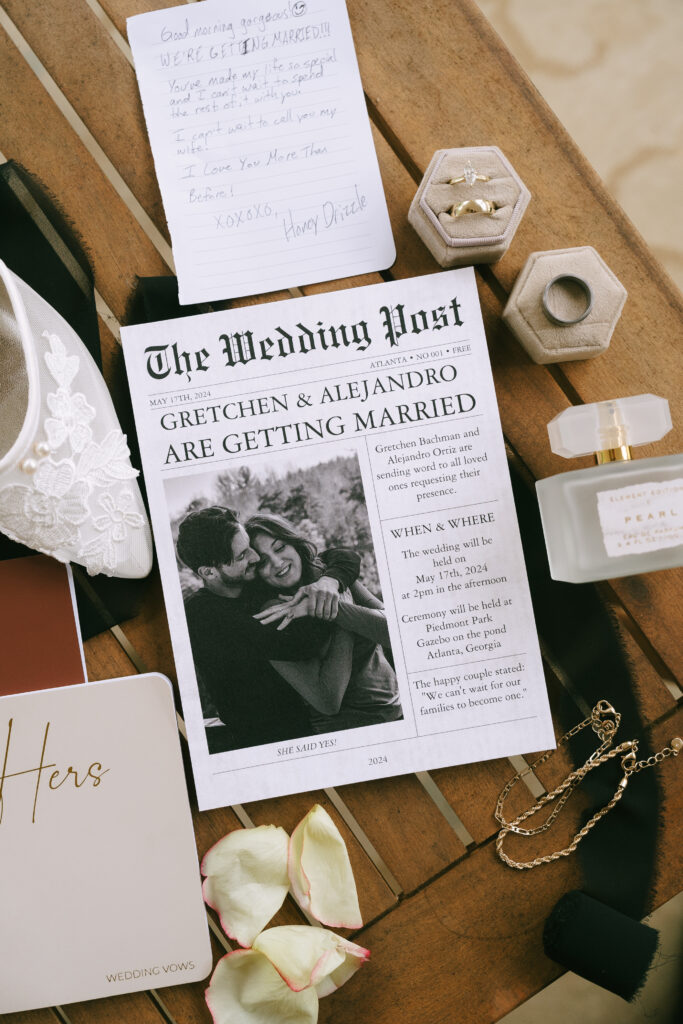 Faux newspaper surrounded by wedding rings, jewelry, perfume, bridal shoes, and vow notebooks.