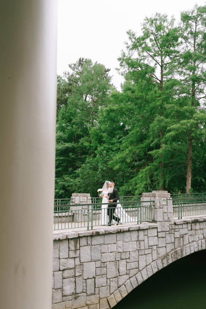 Father of the bride walks bride towards pavilion in Piedmont Park.