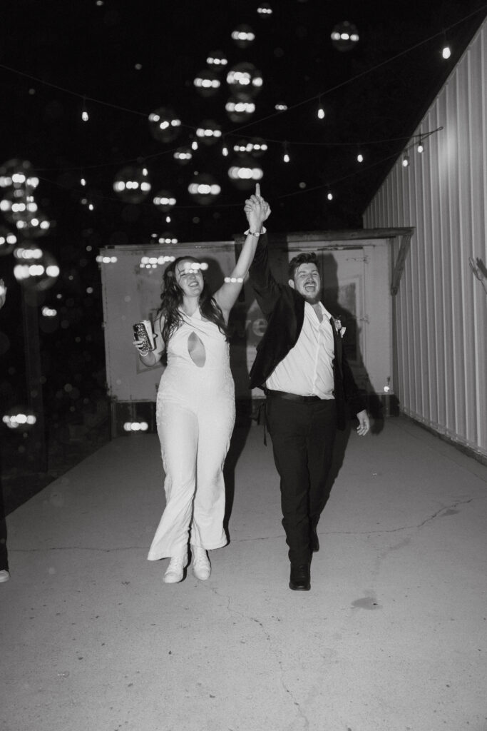 Bride and groom dancing with hands clasped and raised.