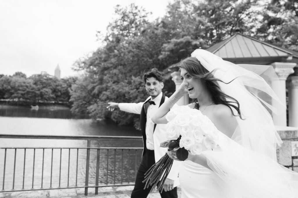 In black and white of bride and groom smiling and walking together in Piedmont Park.