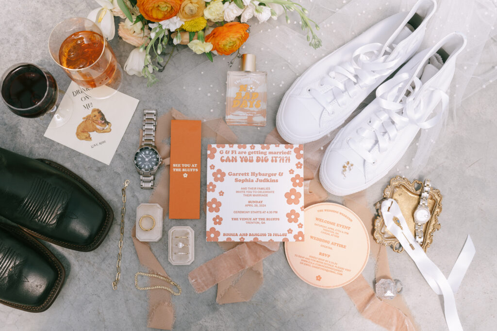 White, pink, and orange invitations, flowers, and ribbons with gold accents with gold jewelry and Rolex watches. White embroidered Converse