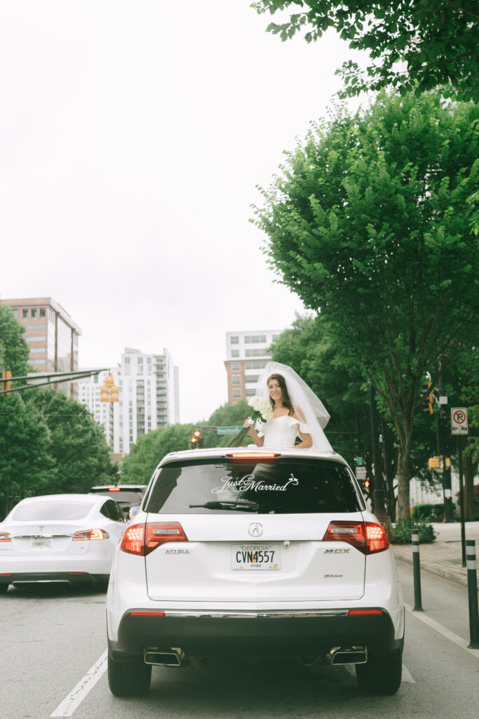 Bride peeking out of sunroof of the "Just Married" getaway car.