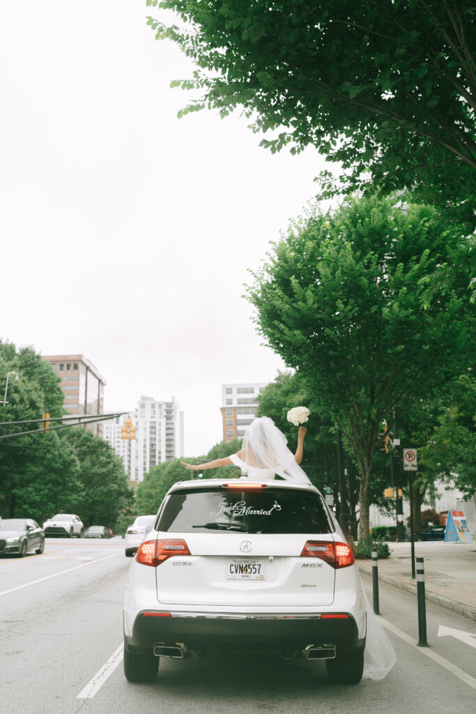 Bride peeking out of sunroof of the "Just Married" getaway car.