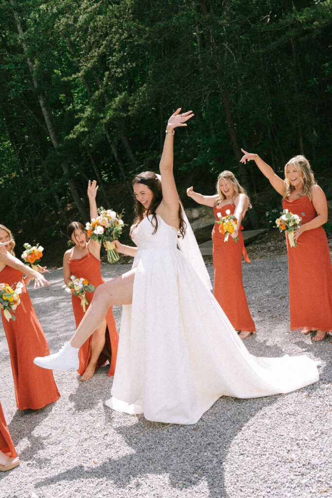 Bride cheering and dancing with bridesmaids cheering behind.