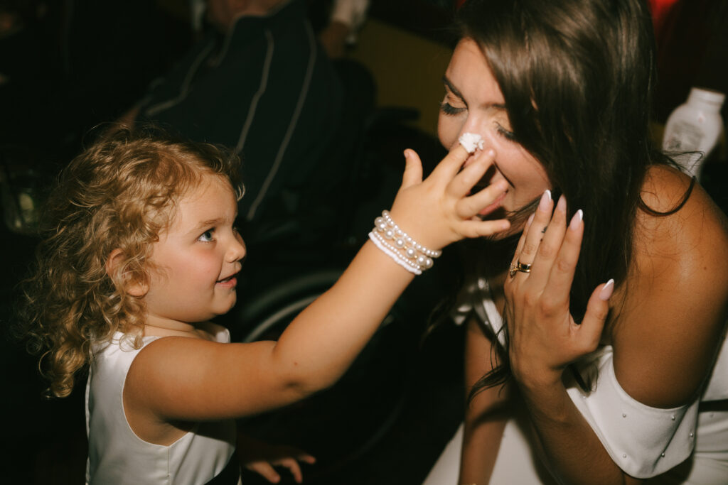 Daughter puts frosting on mother's nose at wedding.