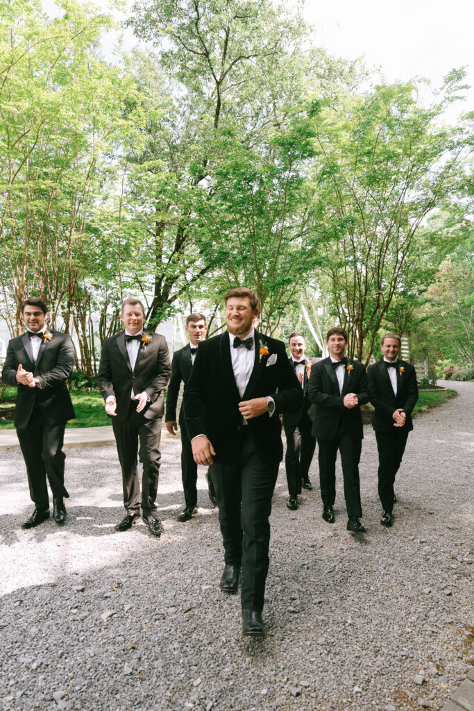 Groom and groomsmen smiling and walking.