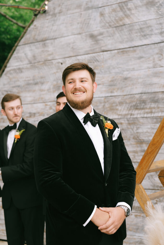 Groom smiling in black tuxedo.