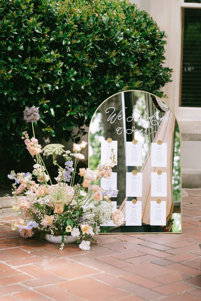 Bouquet of pastel flowers beside a rounded mirror with seat assignments