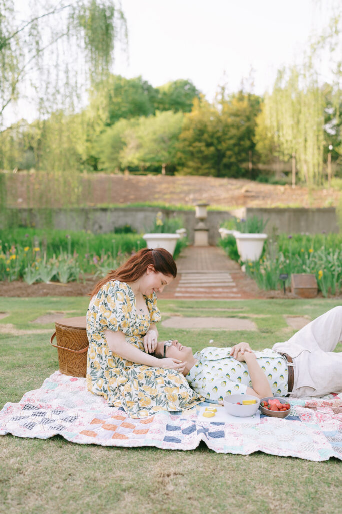 Couple laying together on a picnic blanket, smiling at each other in the State Botanical Gardens of Georgia.